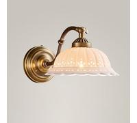 Antique brass wall light in vintage style with a perforated white ceramic shade and curved arm. Single-bulb light suitable for bedrooms, hallways, living rooms, and bathrooms. Hardwired.