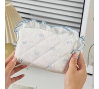 Soft quilted cosmetic pouch with blue bow print and ruffle trim, made for organizing makeup, small beauty tools, and daily essentials at home or on the go.